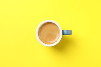 Photo of Aromatic coffee in cup on yellow background, top view