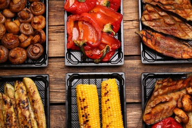 Photo of Plastic containers with different grilled meal on wooden table, flat lay. Food delivery service