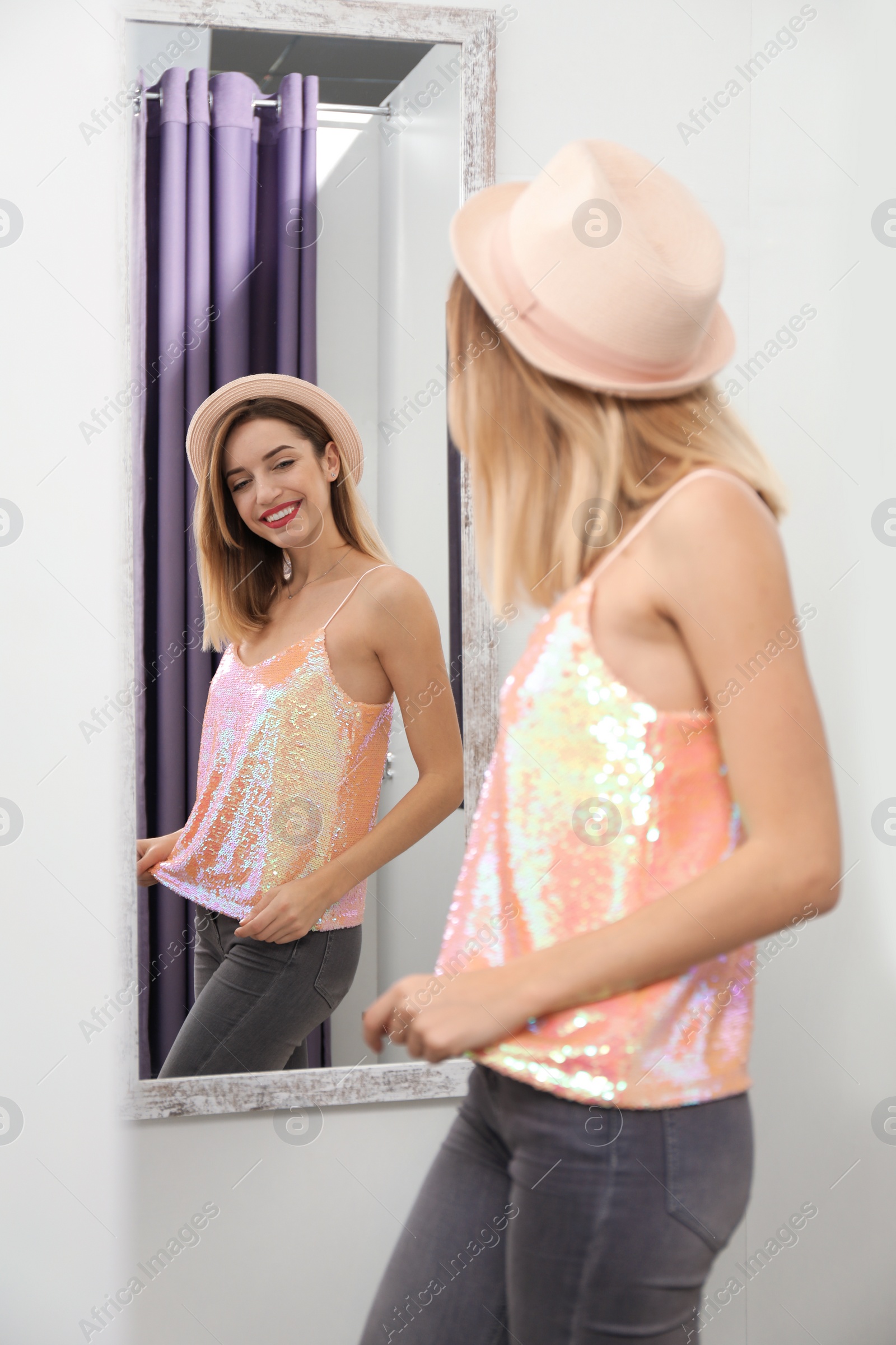 Photo of Young woman trying on clothes in dressing room. Fashion store