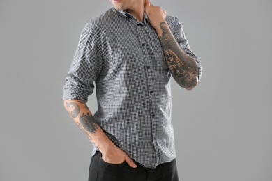 Photo of Young man with stylish tattoos on grey background