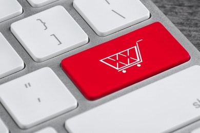 Image of Online store. Red button with shopping cart on computer keyboard, closeup