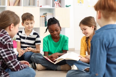 Photo of Cute children discussing homework in classroom at school