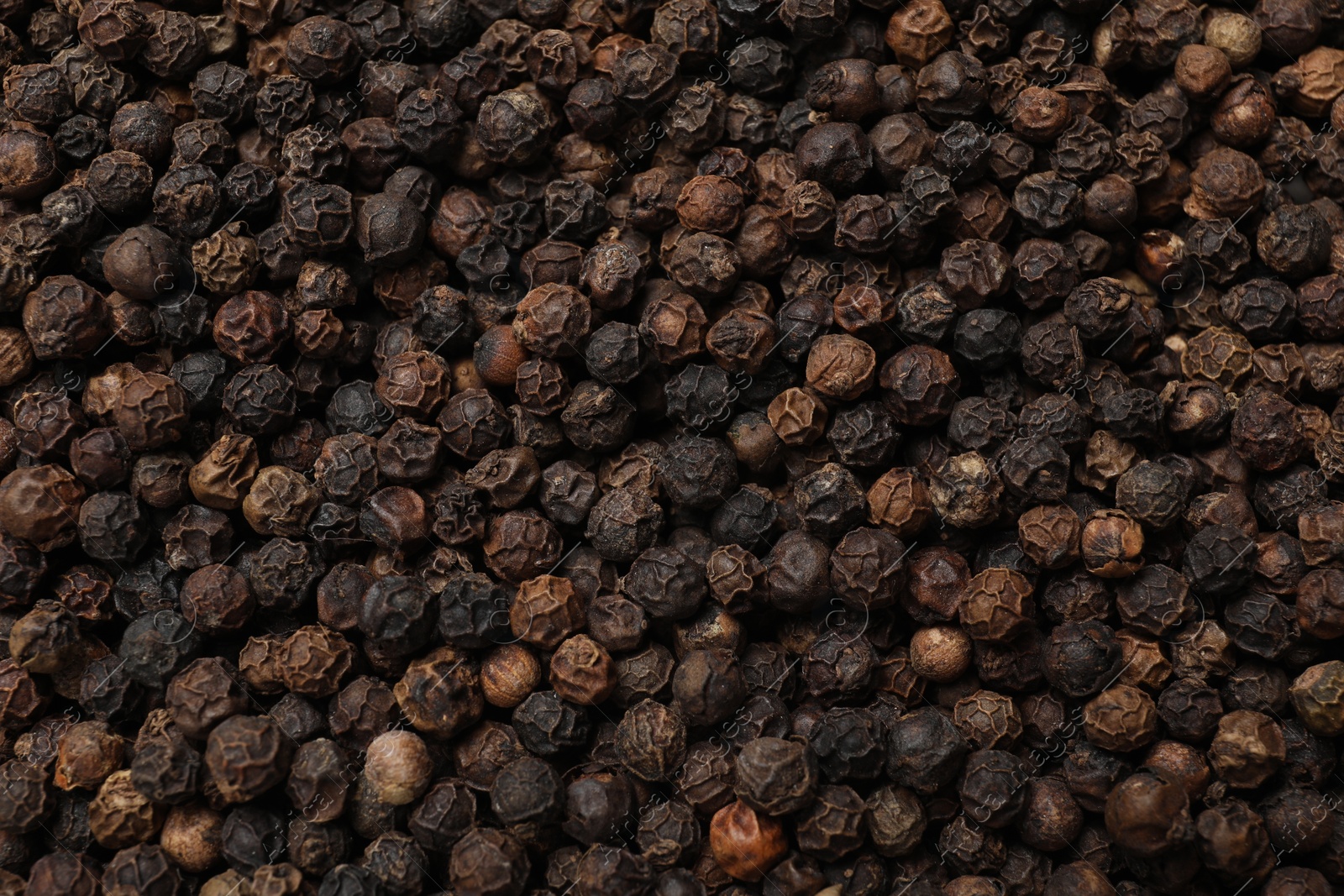 Photo of Aromatic spice. Black peppercorns as background, top view