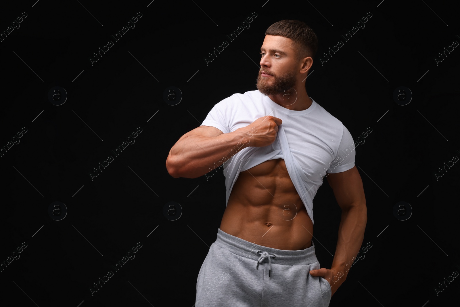 Photo of Young bodybuilder showing his muscular body on black background, space for text