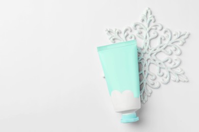 Winter skin care. Hand cream and decorative snowflake on white background, top view. Space for text