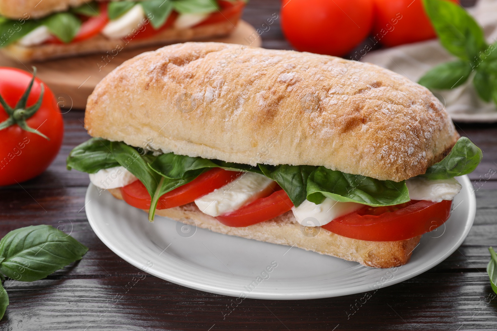 Photo of Delicious Caprese sandwich with mozzarella, tomatoes and basil on wooden table, closeup