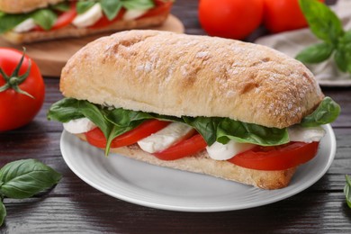 Photo of Delicious Caprese sandwich with mozzarella, tomatoes and basil on wooden table, closeup