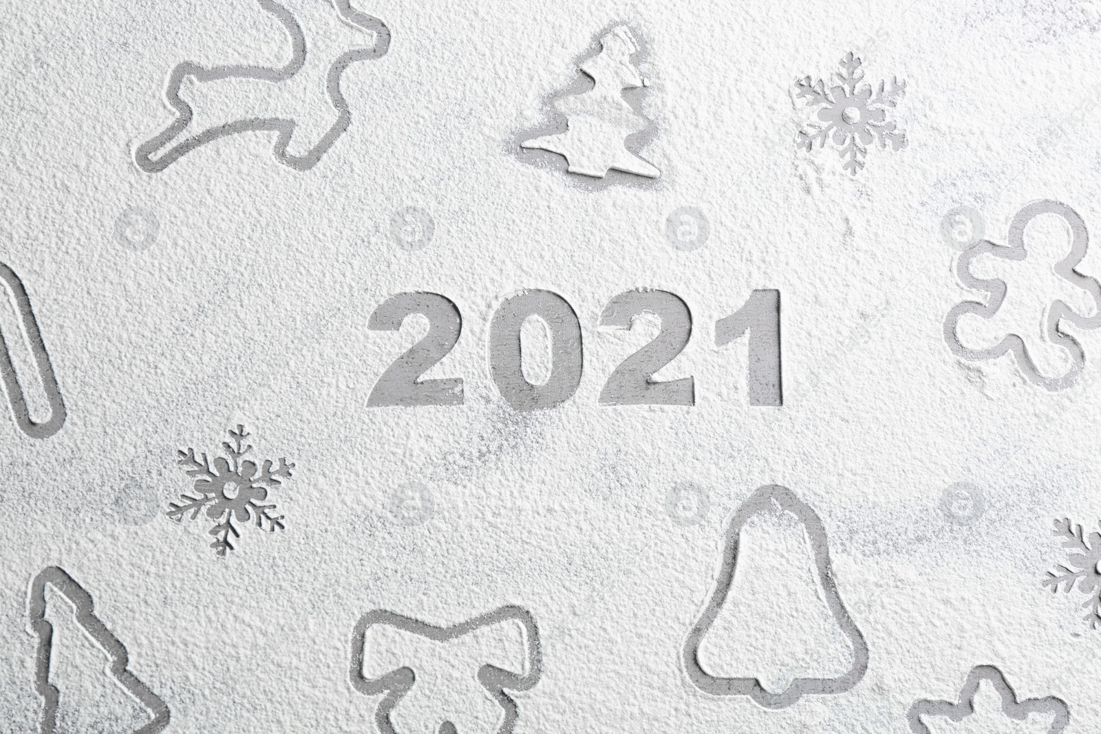 Photo of Different Christmas cookie shapes and number 2021 made of flour on grey table, top view