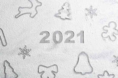 Photo of Different Christmas cookie shapes and number 2021 made of flour on grey table, top view