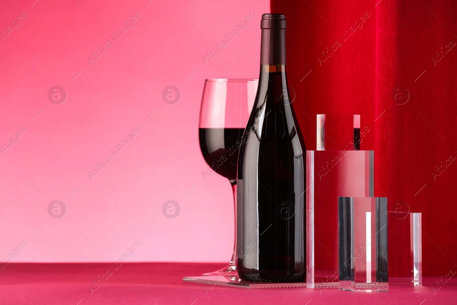 Photo of Stylish presentation of delicious red wine in bottle and glass on color background. Space for text