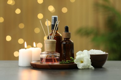 Composition with different spa products and burning candles on light grey table