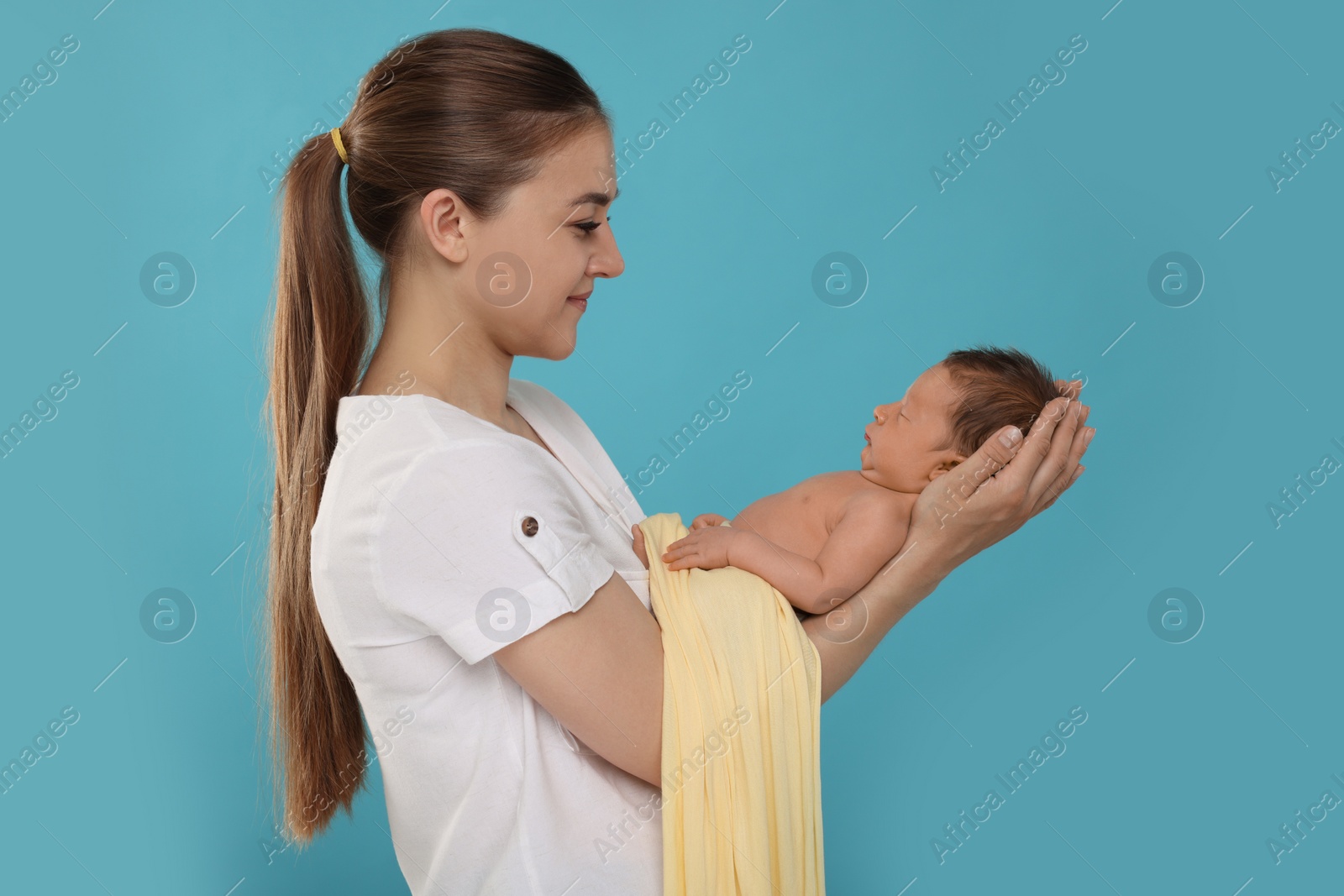 Photo of Mother with her cute newborn baby on light blue background