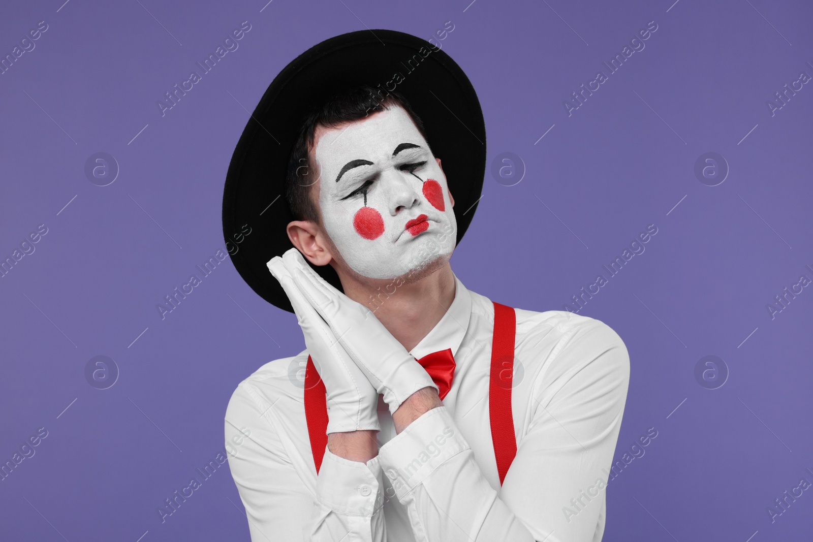 Photo of Mime artist in hat posing on purple background