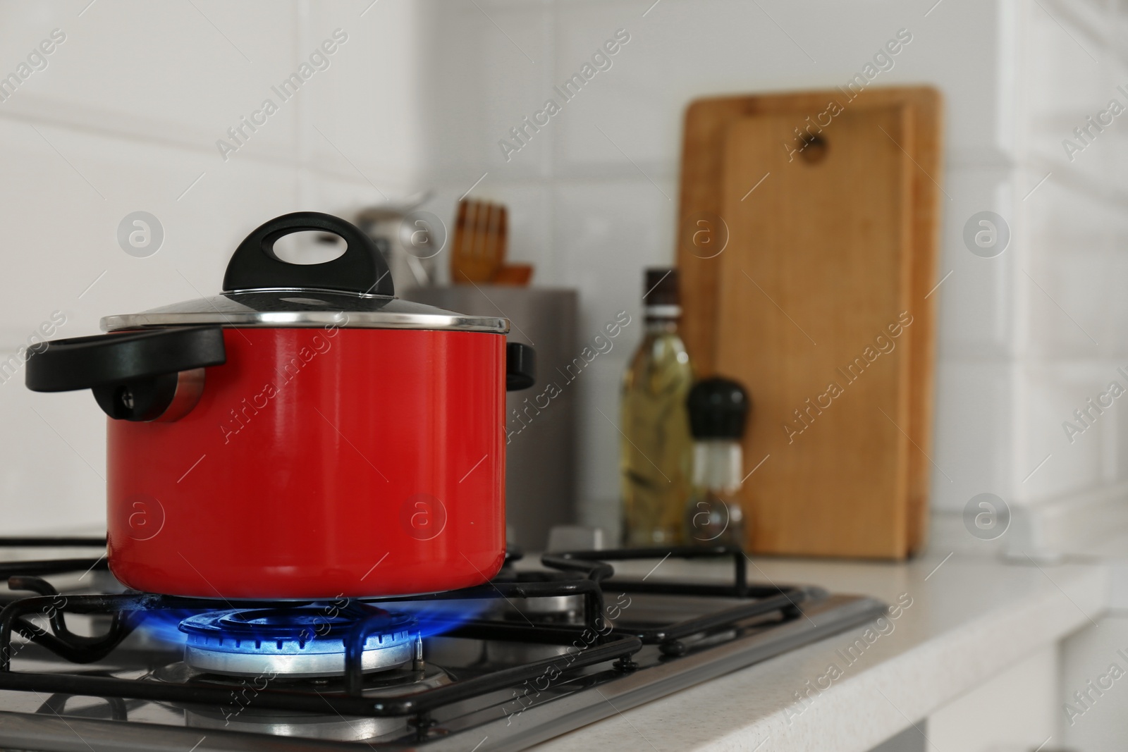 Photo of Red pot on modern kitchen stove with burning gas. Space for text