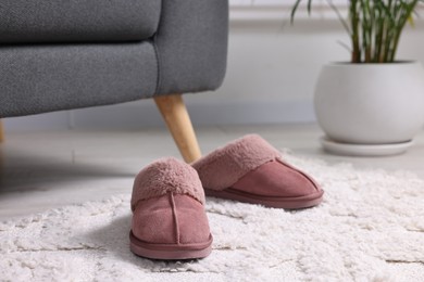 Photo of Pink soft slippers on light carpet indoors