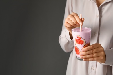 Woman holding fig smoothie on grey background, closeup. Space for text