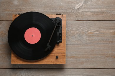 Photo of Turntable with vinyl record on wooden background, top view. Space for text