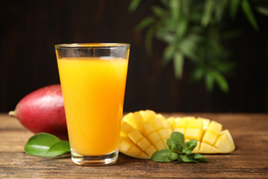 Photo of Fresh delicious mango drink on wooden table. Space for text