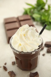 Photo of Glass of delicious hot chocolate with whipped cream on light table, closeup