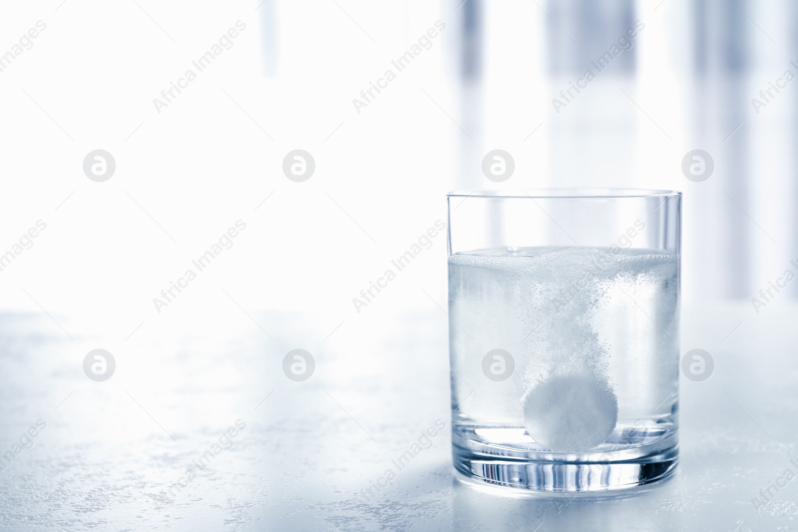 Photo of Glass of water with effervescent tablet on light table indoors, space for text