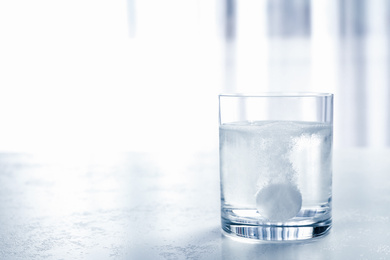 Photo of Glass of water with effervescent tablet on light table indoors, space for text