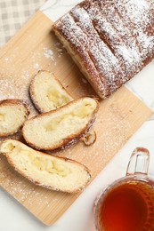 Pieces of delicious yeast dough cake and tea on white table, flat lay