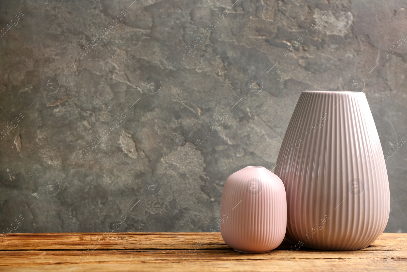 Photo of Stylish empty ceramic vases on wooden table against grey background. Space for text