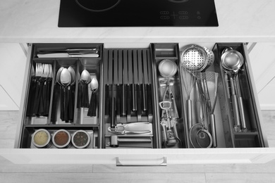 Photo of Open drawer with stainless steel utensil set. Order in kitchen