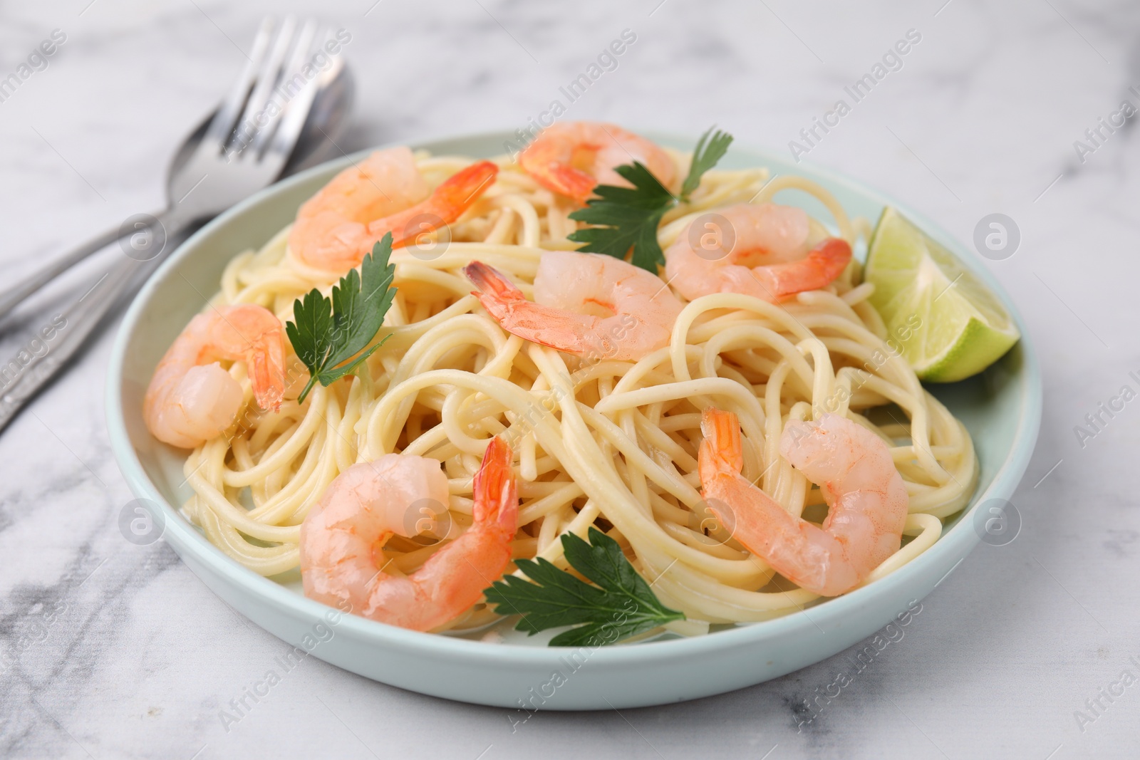 Photo of Tasty spaghetti with shrimps, lime and parsley on white marble table, closeup