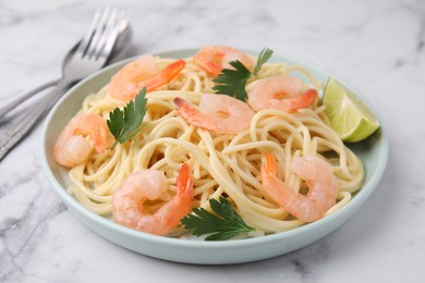 Tasty spaghetti with shrimps, lime and parsley on white marble table, closeup