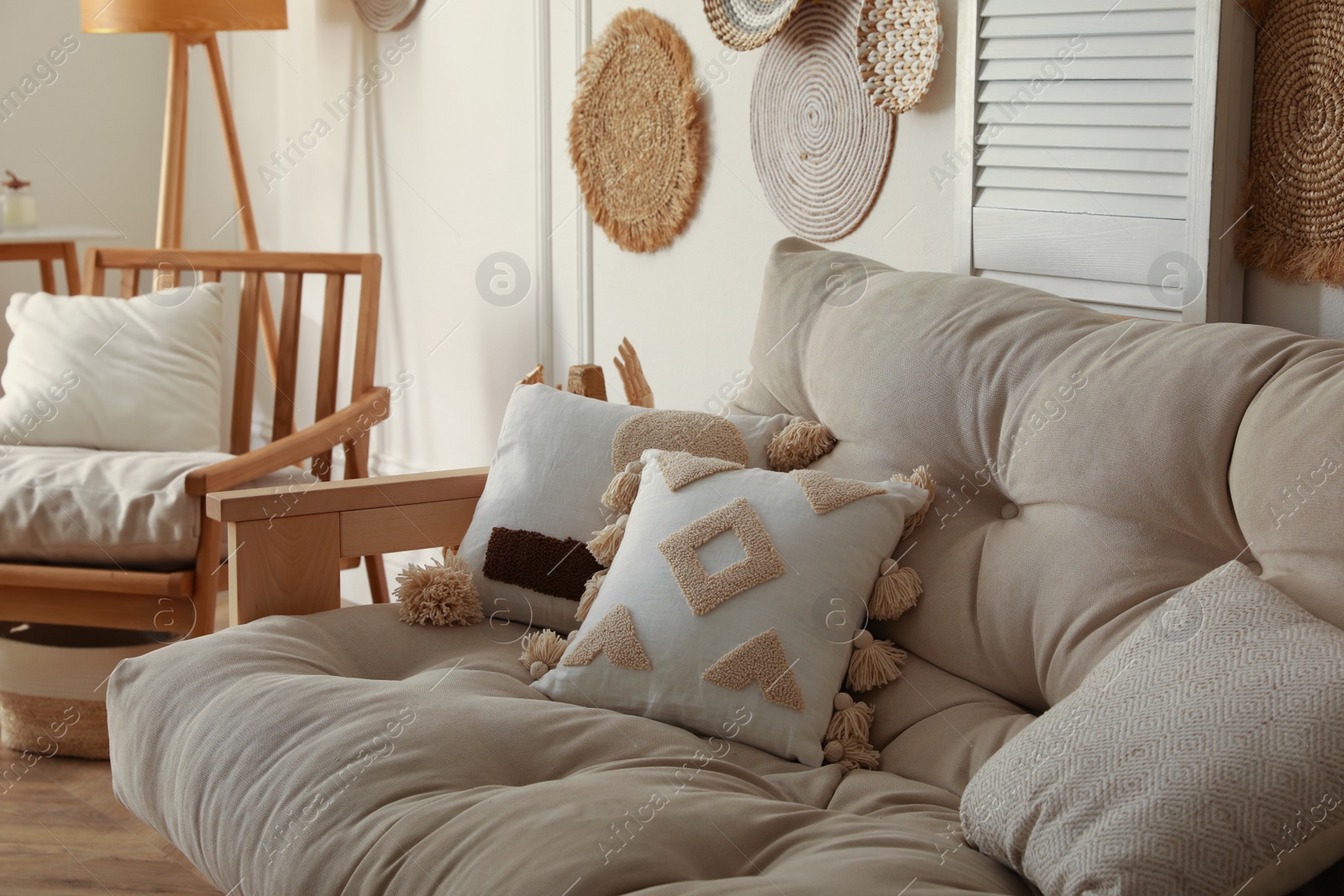Photo of Comfortable sofa near wooden armchair in living room. Interior design