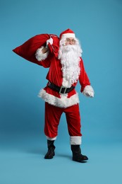 Photo of Santa Claus with bag of Christmas gifts posing on light blue background
