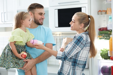 Happy family with products near refrigerator in kitchen