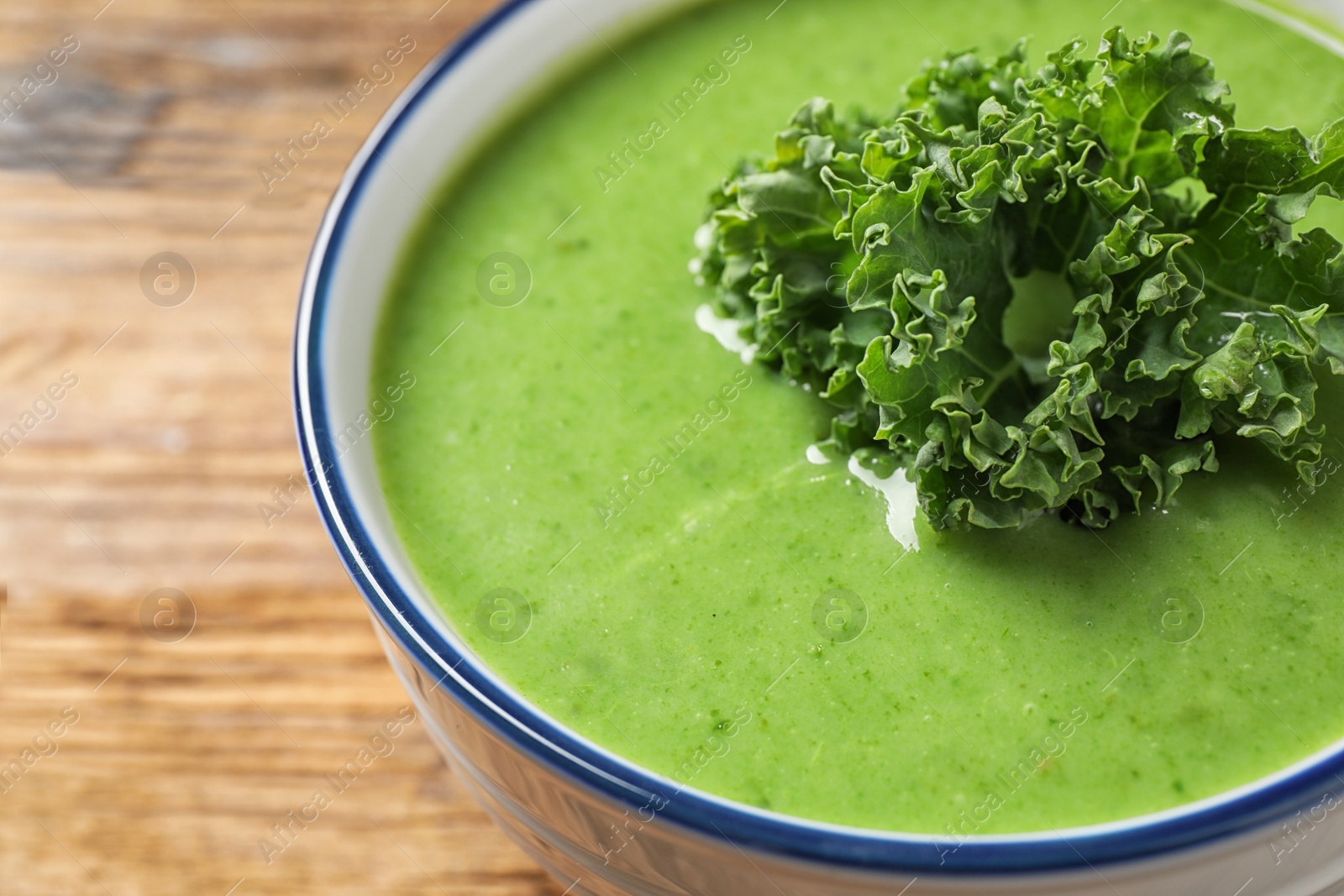 Photo of Tasty kale soup on wooden table, closeup