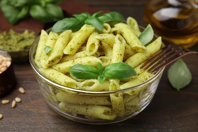 Delicious pasta with pesto sauce and basil on wooden table, closeup