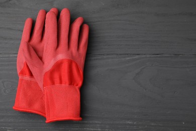 Photo of Pair of red gardening gloves on grey wooden table, top view. Space for text