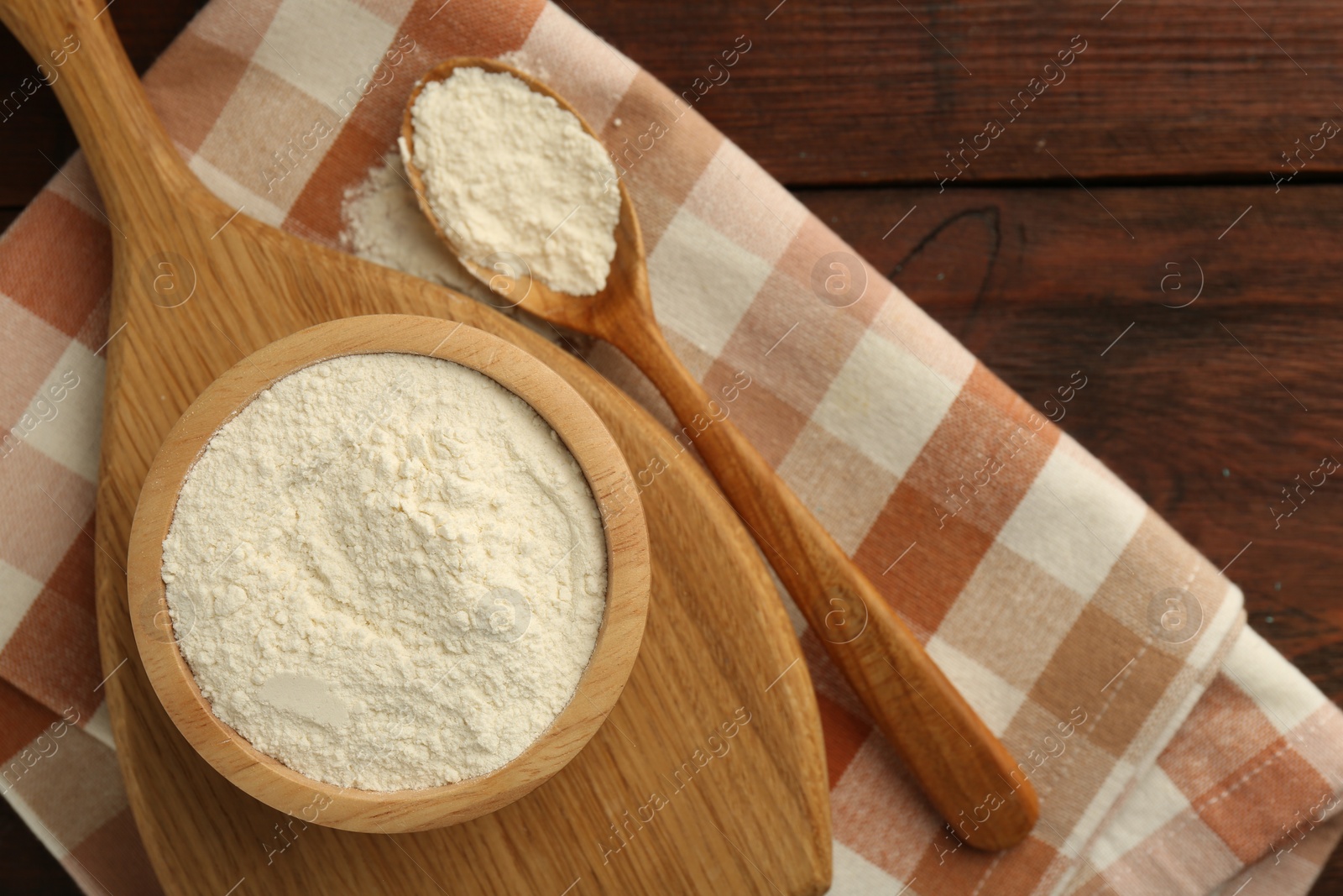 Photo of Baking powder in bowl and spoon on wooden table, top view