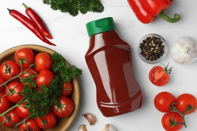 Photo of Bottle of tasty ketchup and ingredients on white marble table, flat lay