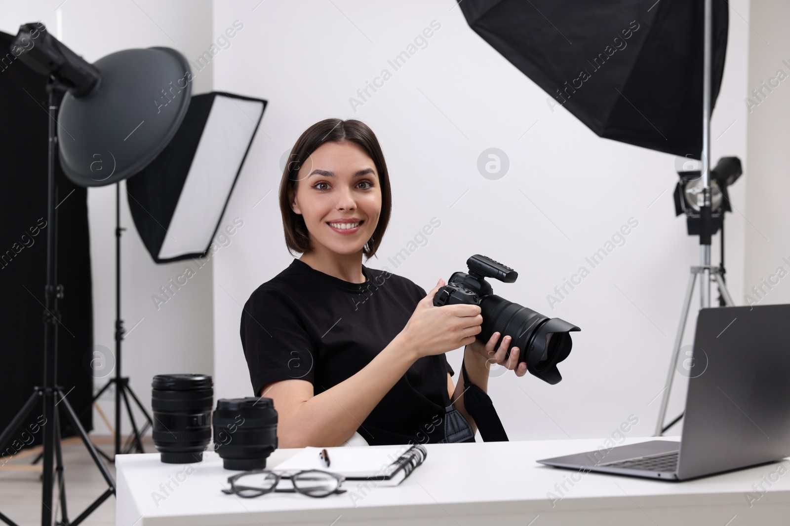 Photo of Young professional photographer with camera at table in modern photo studio