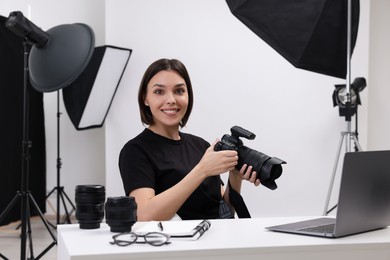 Photo of Young professional photographer with camera at table in modern photo studio