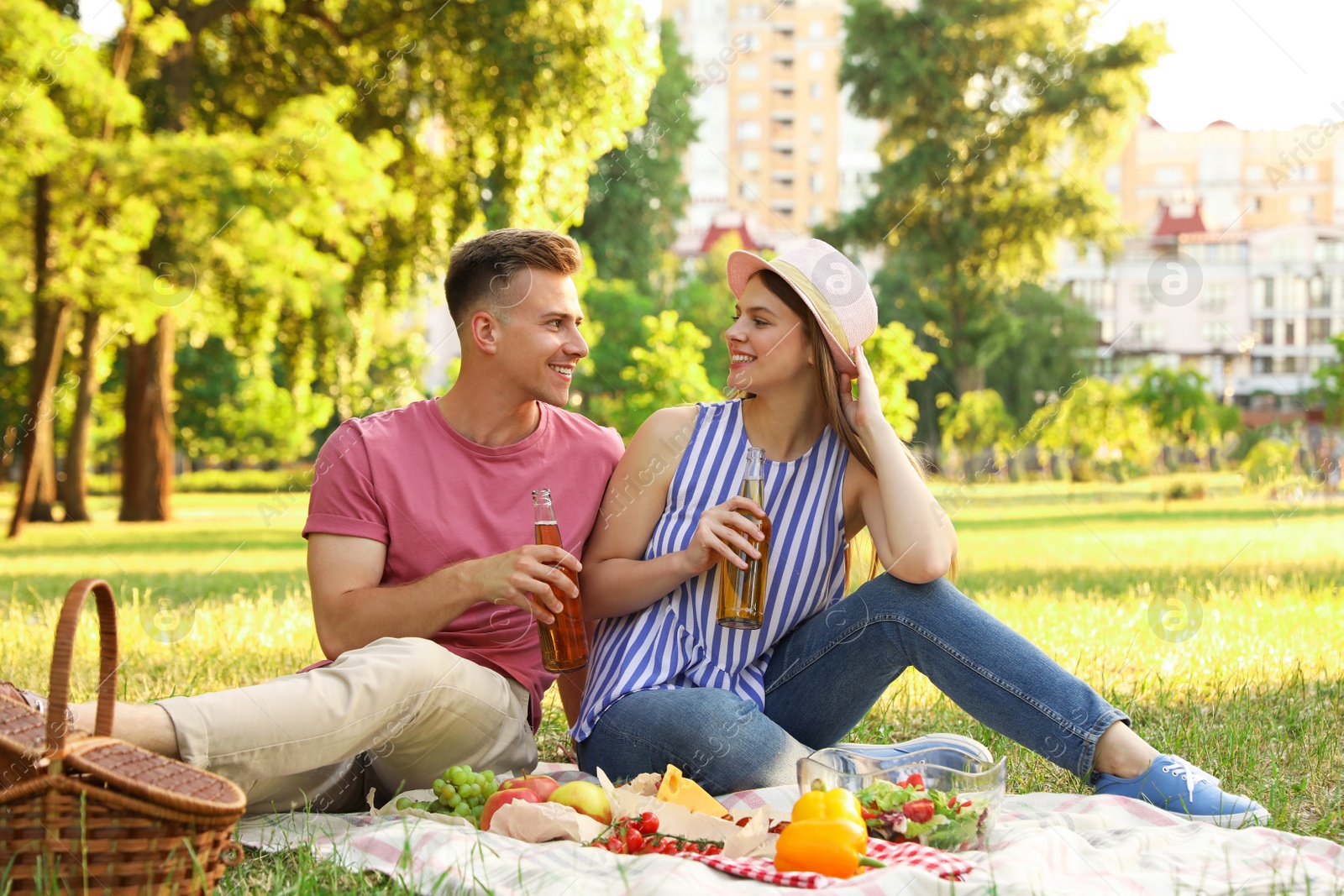 Photo of Young couple enjoying picnic in park on summer day