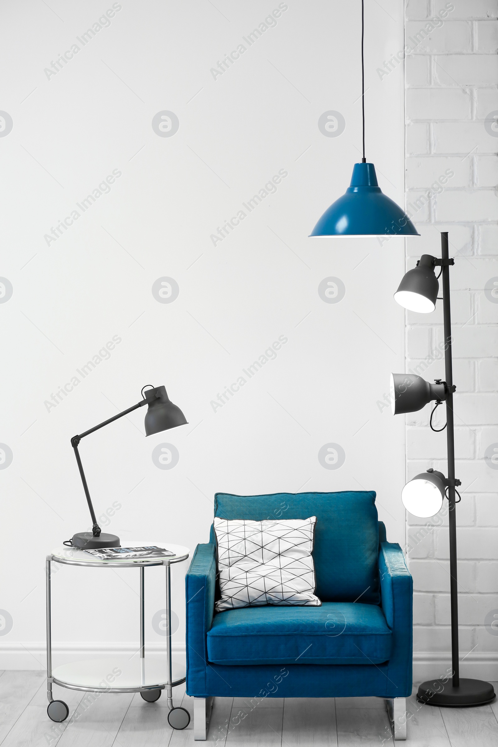 Photo of Modern lamps with blue armchair indoors