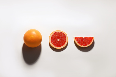 Photo of Cut and whole ripe grapefruits on white background, flat lay