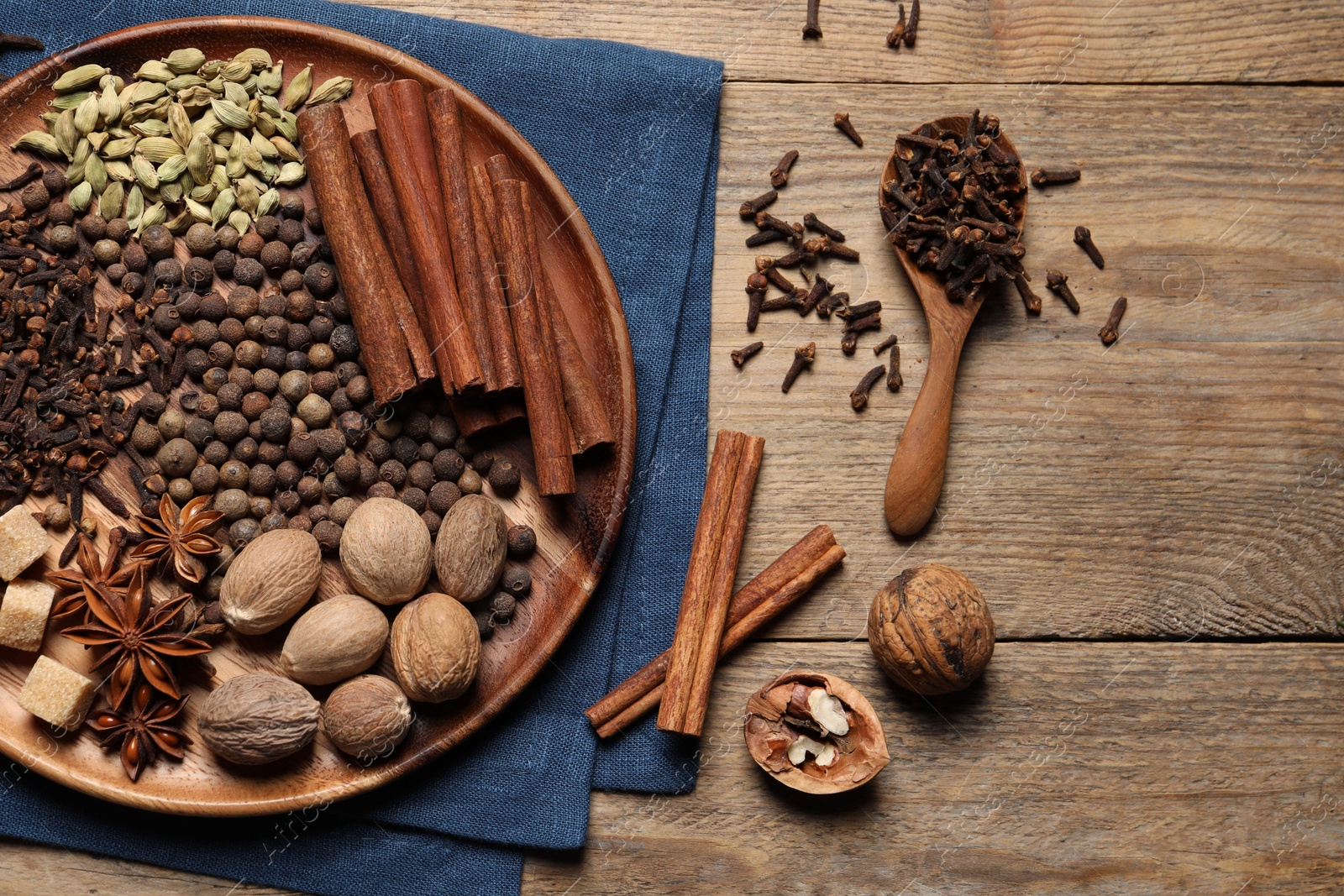 Photo of Spoon with different spices and nuts on wooden table, flat lay