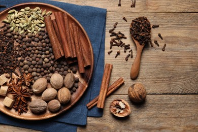 Photo of Spoon with different spices and nuts on wooden table, flat lay