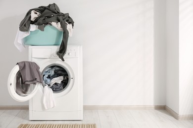 Photo of Laundry basket with clothes on washing machine indoors, space for text