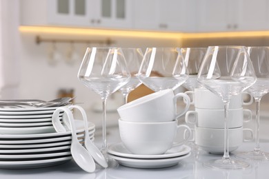 Photo of Set of clean dishware, glasses and cutlery on table in kitchen