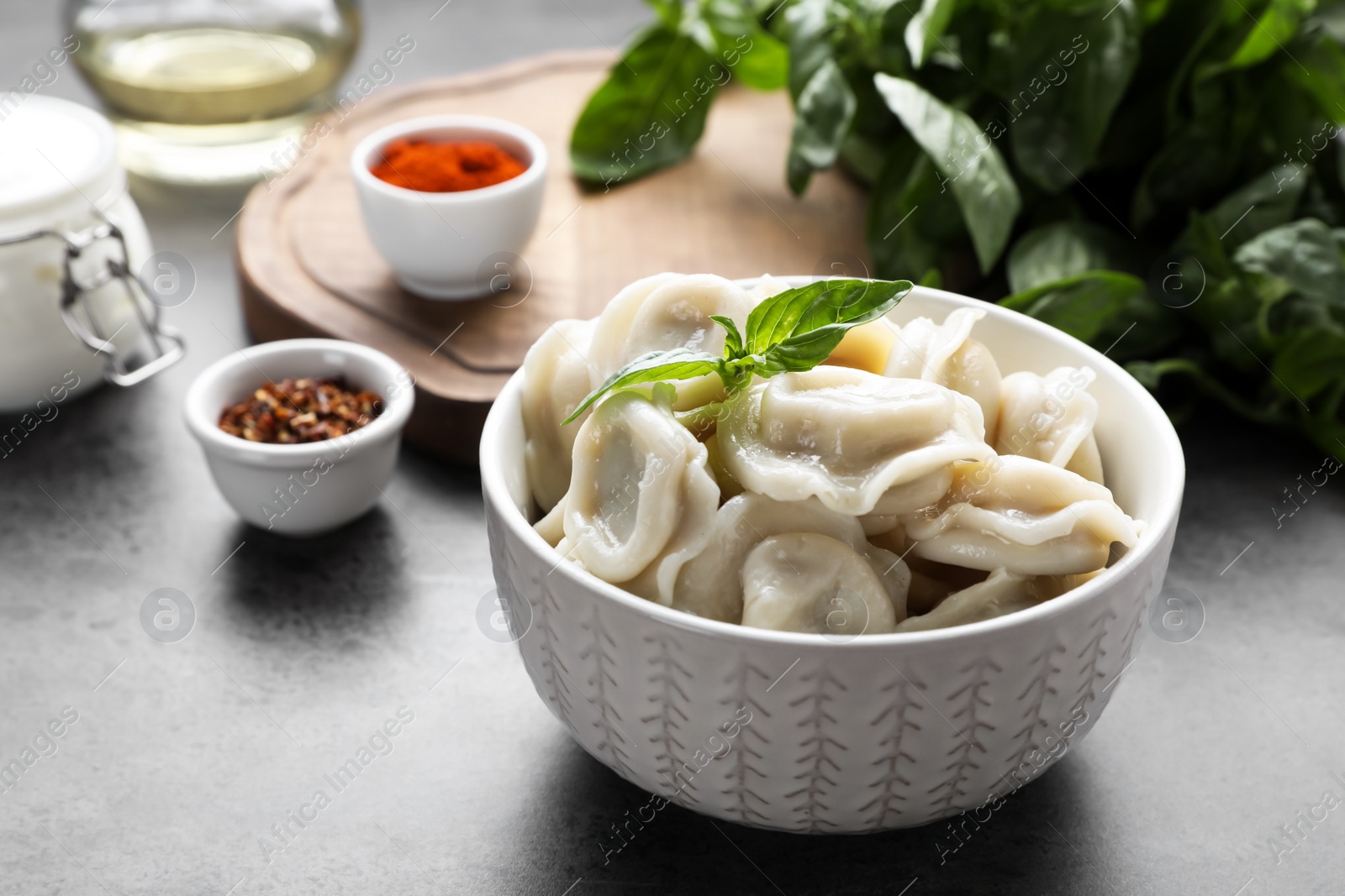 Photo of Tasty dumplings in bowl on served grey table