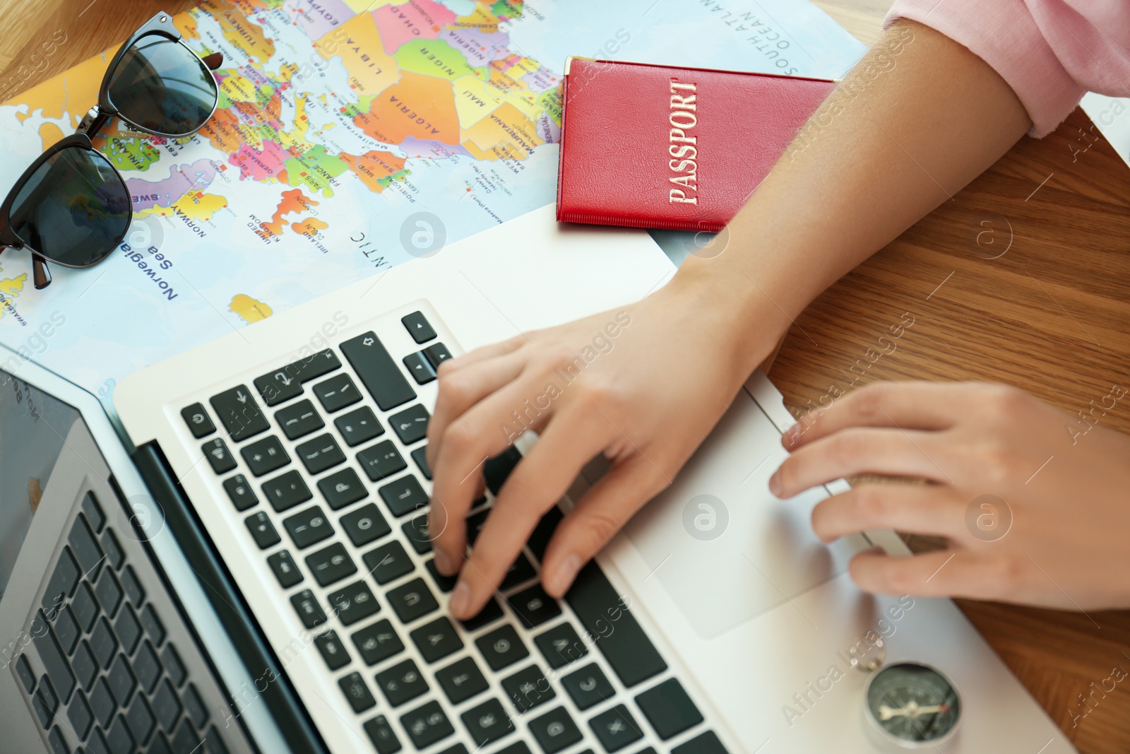 Photo of Woman using laptop to plan trip at wooden table, closeup