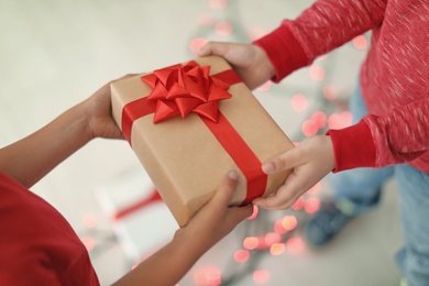 Cute little children with Christmas gift indoors